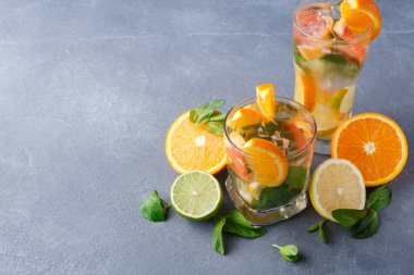 Taze içeceklerle dolu iki bardak taze narenciye meyvelerinin yanına oturur. İçkilerin etrafına nane yaprağı, portakal, limon ve limon dilimleri dizilir. Yaz toplantısı gibi görünüyor..