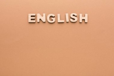 Tahta harfler, düz, açık kahverengi bir yüzeye yerleştirilmiş İngilizce sözcüğünü oluşturur. Ayarlama dikkat dağıtıcı bir şey olmadan metni vurgular, sözcüğe odaklanır.