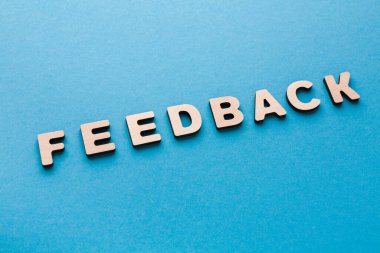 Tahta harfler, düz mavi bir yüzeyde geri bildirim oluşturur. Bu kurulum gelişim ve iletişim üzerine tartışmalar için uygundur. Sahne basit ve doğrudan..