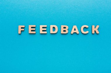 Ahşap harfler mavi bir yüzeyde geri bildirim oluşturmak için dizilmiş. Bu ayar, anketlerde veya değerlendirmelerde yanıtlar ve görüşler hakkında tartışmalar için uygundur.