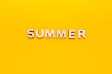 Yazı heceleyen tahta harfler sarı arka planda düzenlenir. Ortam aydınlık ve neşeli, tipik bir yaz mevsimi. Renkler birbirini tamamlıyor..