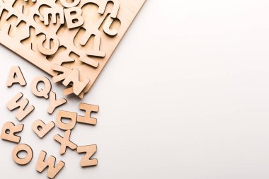 Tahtaya tahta harfler dizilir. Bazı harfler düzgünce yerleştirilirken, diğerleri ışık yüzeyine saçılmıştır. Çocuklar için eğitici bir aktivite ve öğrenme.