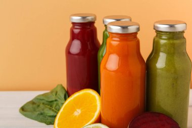 Renkli sıvılarla dolu dört cam şişe bir masaya yerleştirilir. O cennetlerde meyvalar, portakallar ve pancarlar vardır. Arkaplan turuncu renkli..