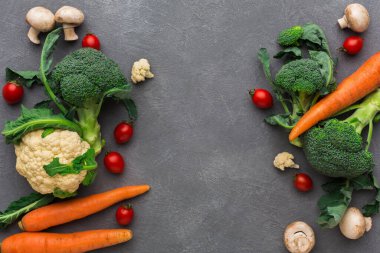 Gri bir yüzeye çeşitli taze sebzeler yerleştirilmiştir. Sahneyi brokoli, havuç, kiraz domatesleri, karnabahar ve mantarlar dolduruyor. Sebzeler çiğ ve pişmeye hazır..