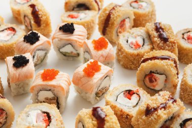 Basit bir arkaplanda gösterilen çeşitli deniz ürünleri ve malzemeleriyle çeşitli roller içeren suşi tabağı