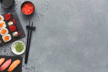 Gri bir yüzeyde bir suşi seçimi düzenlenir. Suşi çeşitli çeşitleri ve renkleri içerir. Yemek çubukları, wasabi, zencefil turşusu ve suşinin yanında küçük bir tabak soya sosu var..