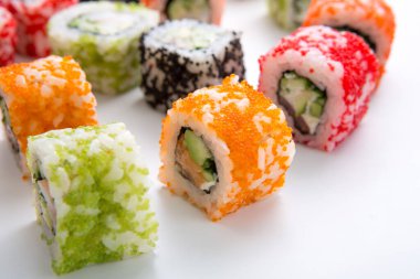 Renkli suşi ruloları beyaz bir yüzeye yerleştirilir. Ekmeğin farklı malzemesi ve dolgusu var. Bu sahnede gündelik bir yemek sırasında çok çeşitli suşiler var..