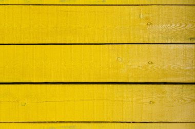 Sarı ahşap tahtalar düz bir yüzeyde yan yana dizilir. Tahtanın dokusu görülebilir, düğümler ve çizgiler görünüyor. Rengi canlı ve parlak..
