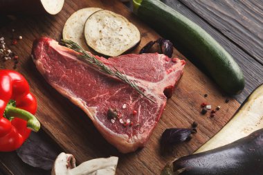 Ahşap bir tahta taze sebzelerin yanında çiğ et tutar. Dolmalık biber, kabak, patlıcan ve otlar pişirmek için ayarlandı. Sahne yemek hazırlıklarını gösteriyor..