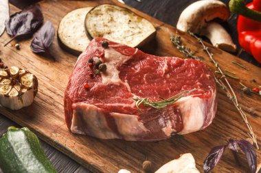 Bir kolaj ahşap bir tahtanın etrafına çeşitli sebzelerle yerleştirilmiş taze et kesiklerini gösteriyor. Mantar, patlıcan ve bitkiler gibi malzemelerle bir yemek hazırlamak için sahne hazırlandı..