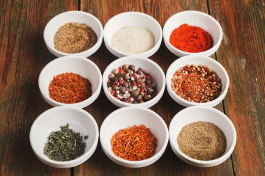 Baharatlar ahşap bir masanın üzerindeki küçük beyaz kaselere konur. Kaseler şebeke şeklinde dizilmiş. Her kasede farklı bir baharat var. Renkler kırmızıdan kahverengiye değişir.