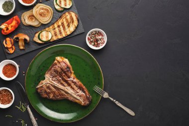 Çeşitli ızgara et ve sebzeler karanlık bir masada düzenlenir. Ana yemeğin etrafına baharat ve bitkiler saçılmış. Bu sahnede bir yemek hazırlığı sergileniyor..