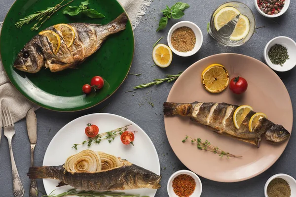 Limon, otlar ve vişneli domateslerle süslenmiş üç tabak balık. Çevreleyen kaseler çeşitli baharatlar içerir. Sahne çeşitli mutfak sunum stillerini yakalar.