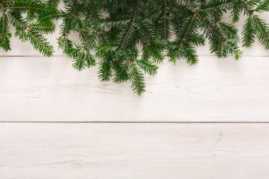 Yeşil dallar açık ahşap bir yüzeye serilmiştir. Dekorasyon, tatil süslemeleri ve mevsimlik etkinliklerle ilgili bir kış temasını ortaya koyuyor.