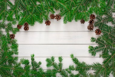 Çam dalları ve koniler ahşap bir yüzey etrafında bir mozaik oluşturur. Yeşillik ve doğal şekiller birleşerek sanatsal bir koleksiyon oluşturur. Bu sahne doğal elementleri kullanarak mevsimsel güzellikleri yakalar..