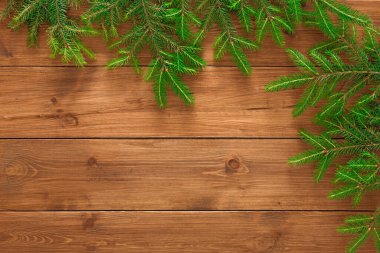Yeşil çam dalları ahşap bir yüzeye dizilmiştir. Sahne, ahşap ve yaprakların çeşitli dokularını gösteriyor. Bu, doğal elementlerin hoş bir koleksiyonunu yaratır..