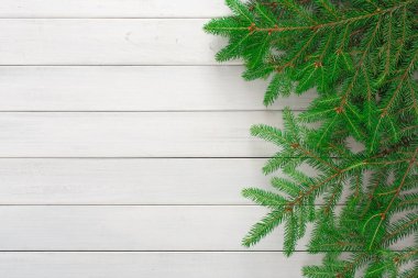 Yeşil çam dalları beyaz ahşap bir yüzeyde duruyor ve doğal bir ortam yaratıyor. Bu koleksiyon, basit bir arkaplan ile birlikte çam ağacının dokusunu ve rengini vurgular.