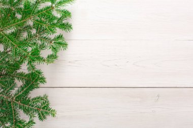 Yeşil dallar hafif bir ahşap yüzeye yayılır. Bu dallar dekorasyon ya da el işi projeleri için kullanılabilir. Doğal dokusu pürüzsüz ahşap zemin ile çelişiyor..