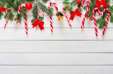 Bir dizi tatil süslemesi kolaj biçiminde gösterilir. Şeker kamışları, kurdeleler ve çanlar beyaz ahşap bir yüzeye yerleştirilmiştir. Çam dalları neşeli bir görüntü katar, neşeli bir sahne yaratır..