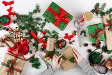 Eller hediyeler, kurdeleler ve yeşil yapraklarla dolu bir masaya hediye paketler. Tatil hazırlıkları için çeşitli malzemelerin düzenlenmesiyle ortam şenlik havasına girdi..