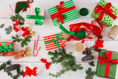 Çeşitli renklerde paketlenmiş hediyeler, kurdeleler, kozalaklar ve tatil süslemeleriyle düz bir zeminde düzenlenir. Hediyelerin etrafına saçılmış şeker kamışı ve yeşillik parçaları var..