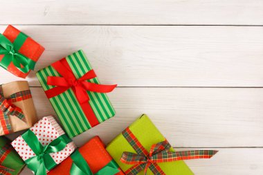 Tahta bir yüzeye çeşitli paketlenmiş hediye kutuları yerleştirilir. Hediyeler farklı tasarım ve renkleri gösteriyor. Kırmızı, yeşil ve altın kurdeleler şenlik havası yaratır. Bu sahne özel bir olay için hazır..