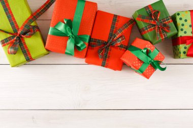 Birkaç paket kırmızı, yeşil ve desenli hediye paketleri ahşap bir masa üzerinde düzenlenir. Hediyeler kurdelelerle bağlanıyor ve neşeli bir sahne yaratıyor. Bu kurgu şenlikli bir etkinlik için mükemmel..