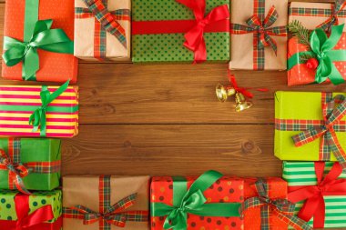 Tahta bir yüzeyde paketlenmiş hediyeler sergilenir. Hediyelerin çeşitli renkleri ve desenleri var. Bazılarının kurdeleleri ve süslemeleri var..