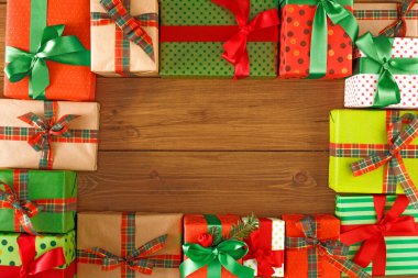 Renkli hediye kutuları ahşap bir masanın üzerinde düzgün bir şekilde düzenlenir. Hediyelerin farklı dizaynları ve fiyonkları var. Bu düzen özel durumlar için idealdir..