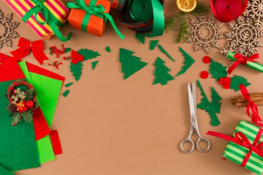 El işi seansı renkli kağıt, makas, kurdele ve süslemelerle dolu bir masada yapılır. Yeşil ağaçlar tatil projeleri için biçilmiş kaftan. Çeşitli ögeler sıralanır.