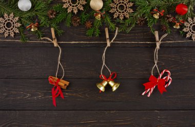 Ahşap bir arka planda çeşitli tatil dekorasyonları düzenlenir. Set, tarçın çubukları, altın çanlar ve kırmızı kurdelelerle bağlanmış şeker kamışlarını içeriyor..