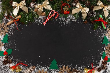 Tatil süslemeleri arasında fiyonklar, baston şekerler ve çam ağaçları yer alıyor. Yeşillik, notlar yazmaya veya kış mevsiminde mesajlar göstermeye hazır siyah bir yüzeyi çevrelemektedir.