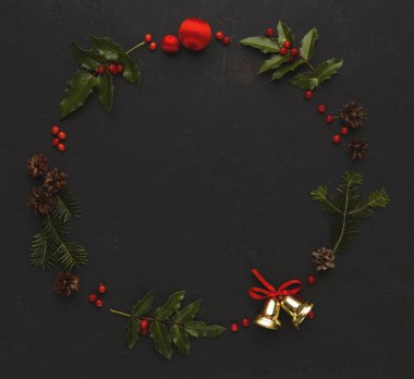 Bir tatil süslemeleri koleksiyonunda yeşil yapraklar, kırmızı böğürtlenler ve daire şeklinde sıralanmış parlak süsler yer almaktadır. Bu kurulum, çam kozalakları ve çanları sergiliyor, neşeli bir görünüm yaratıyor.