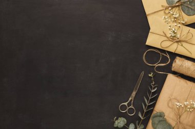 Karanlık bir yüzeye yerleştirilmiş, hediye, sicim, makas, yaprak ve çiçeklerle eşsiz bir kolaj..