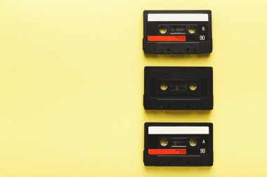 Parlak sarı arka planda dikey olarak dizilmiş üç kaset klasik ses depolama tasarımını gösteriyor. Koleksiyonda renkli etiketli siyah plastik kutular yer alıyor..