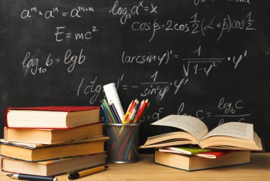 Kitaplar ön tarafında açık bir kitapla ahşap bir masanın üzerine dizilir. Kalem ve kalemlerle dolu bir fincan yakında duruyor. Matematik denklemleriyle kaplı bir karatahta arka planda görünür.