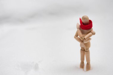 Kırmızı eşarplı tahta manken kar yığınının içinde donuyor. Yalnızlık ve kış modası