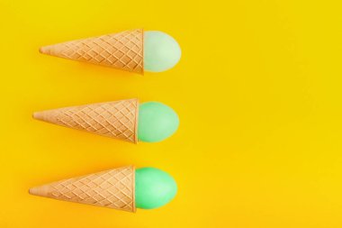 Gözleme koniler sarı zemin üzerine yeşil Paskalya yumurta. Parlak yaratıcı zemin, üstten görünüm, kopya alanı