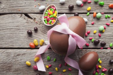 Ahşap arka planda pembe kurdeleli çikolatalı paskalya yumurtaları