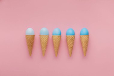 Paskalya geçmişi. Pembe yüzey üzerinde waffle koniler degrade renkli mavi yumurta. Tebrik kartı, mockup, kopya alanı, düz yatıyordu, üst görünüm Minimalistic tasarım