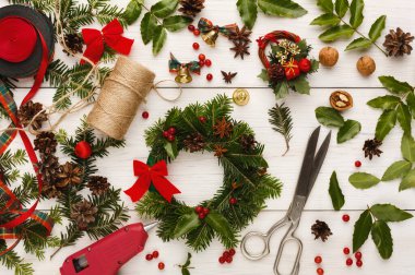 Tatil çelengi yapmak için çeşitli malzemeler. Yeşillik, kurdeleler, dekoratif eşyalar ve aletler var. Ayarlar zanaat faaliyetleri ile bir atölye atmosferi öneriyor.