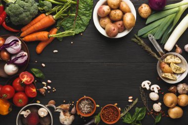 Tahta bir yüzey üzerinde taze sebze ve bitki koleksiyonu sergilenir. Parlak havuçlar, yeşil brokoli ve çeşitli patatesler küçük kaselerde bitki ve baharatlarla çevrilidir..