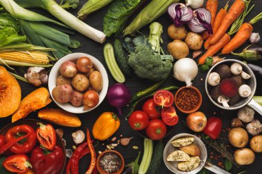 Masada çok çeşitli taze sebzeler sergilenir. Sahnede patates, havuç ve yapraklı yeşillikler de dahil olmak üzere farklı sebze çeşitleri ve renkleri gösteriliyor..