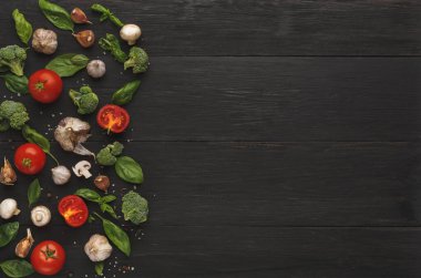 Taze sebzeler koyu ahşap bir yüzeyde güzelce düzenlenir. Domates, sarımsak, mantar ve sebze var. Bu düzenek yemek pişirmek ve sağlıklı beslenmek için gerekli malzemeleri gösteriyor..