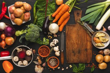 Tahta bir masada çeşitli taze sebzeler sergilenir. Farklı renkler ve sebzeler patates, havuç ve yeşildir. Bazı otlar ve baharatlar da içerir..