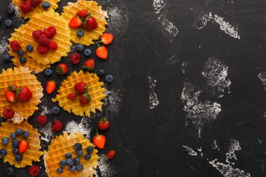 Siyah bir yüzeye bir waffle koleksiyonu yerleştirilir. Waffle 'lar çilek, ahududu ve yaban mersiniyle süslenmiş..