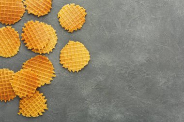 Gri bir yüzeye yuvarlak bir waffle seti yerleştirilir. Waffle 'ların şebeke deseni var ve konumları değişiyor. Kıtır kıtır ve altın kahverengidirler, servis ya da atıştırmaya hazırdırlar..