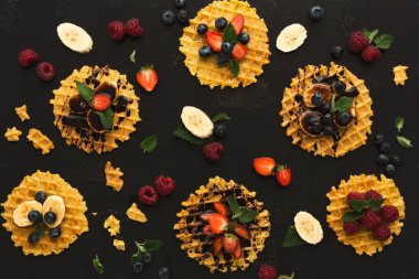 Farklı waffle 'lar karanlık bir yüzeye yerleştirilir. Her waffle 'ın çilek, muz ve yabanmersini gibi çeşitli meyveleri vardır. Bazı waffle 'lar çikolatayla kaplıdır..