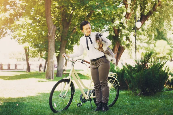 Young woman with dog and bicycle in the park — Stok fotoğraf