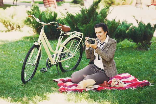 Mujer joven con bicicleta en el picnic en el parque — Foto de Stock